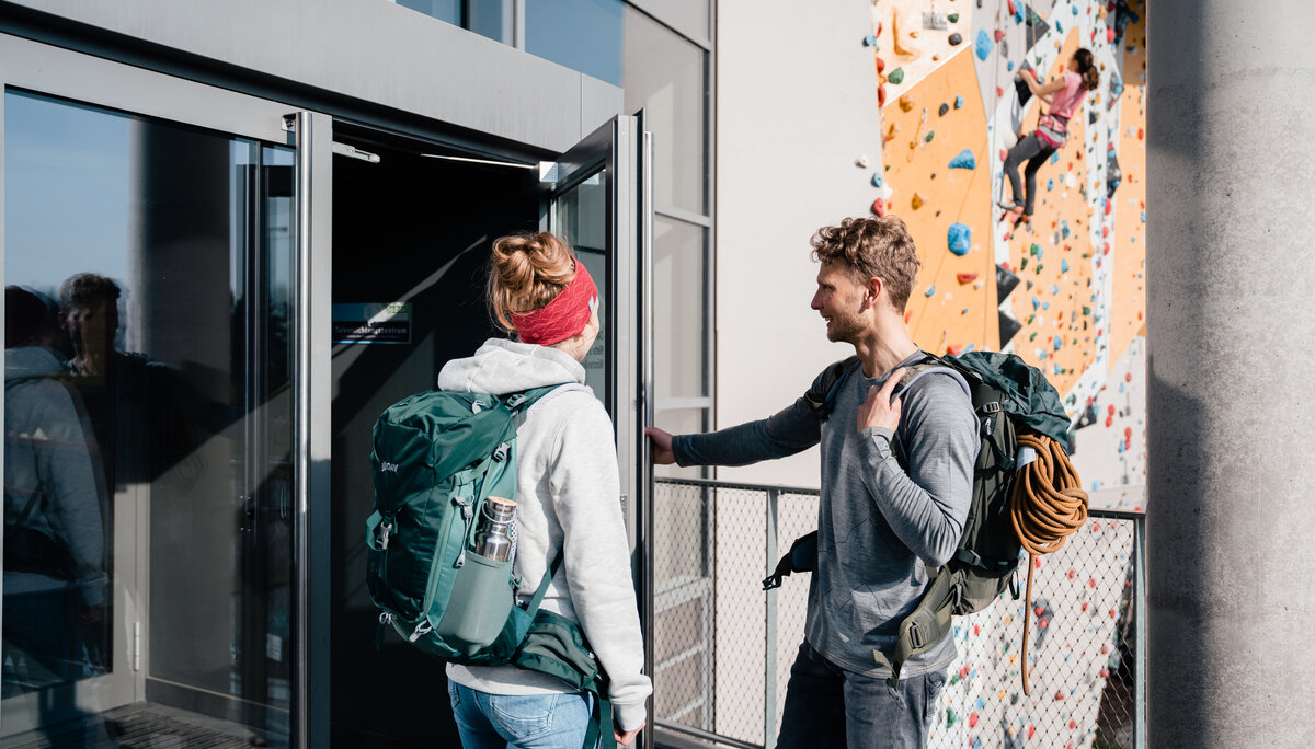 Bouldern und Indoor-Klettern ist bei vielen DAV-Sektionen möglich | © DAV/Marisa Koch Zwei Persinen öffnen die Tür zu einer Boulder- und Kletterhalle | © DAV/Marisa Koch